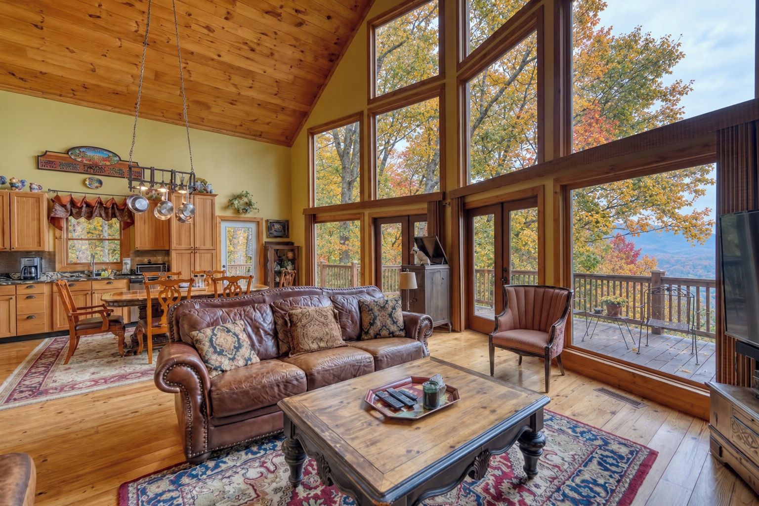 A spacious living room with a large leather sofa, a coffee table, and a dining area with wooden furniture.