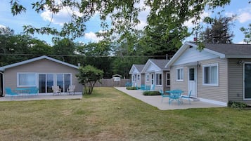 Un quartier résidentiel comprenant deux maisons de plain-pied, une cour clôturée et un espace extérieur aménagé pour s’asseoir.