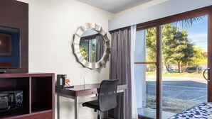 Habitación de hotel con escritorio, silla, cama, televisión y vista a la calle.