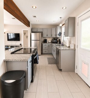 A modern kitchen with a central island, stainless steel appliances, and a large window.