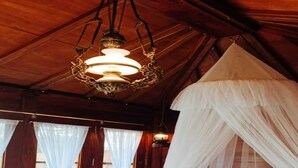 A room with a canopy bed, white curtains, and a hanging light fixture.