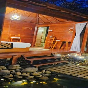 Une cabane en bois avec un lit, une petite table et un banc.