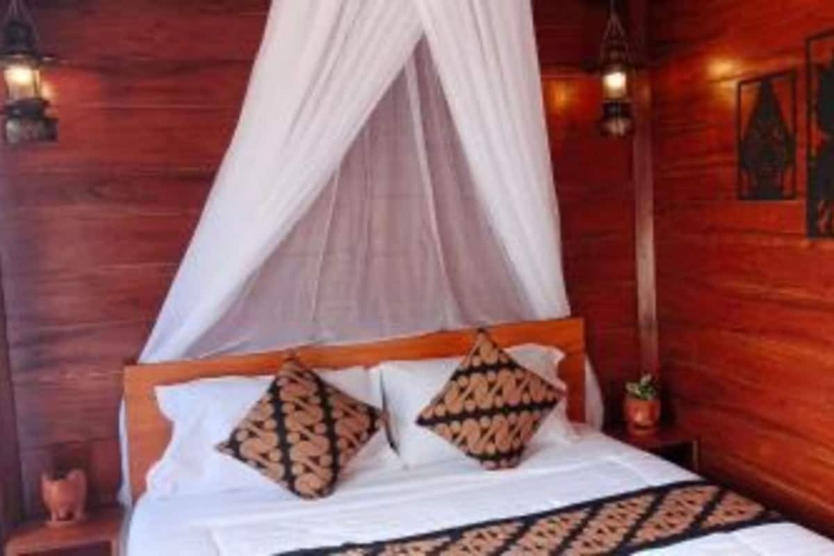Una habitación de madera con una cama, dosel y decoración en las paredes.