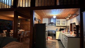 Una cocina rústica con vigas de madera, un refrigerador y un comedor con sillas y una mesa.