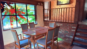 Un comedor con mesa y sillas de madera, una ventana de vitral y una pared de ladrillo.