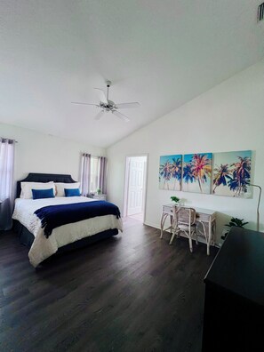 A bedroom with a bed, a desk, and a ceiling fan. - Spacious Florida Pool Retreat - 15 min from beach (Vero Beach)