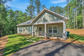 A two-story house with a front porch, stone pillars, and a mailbox.