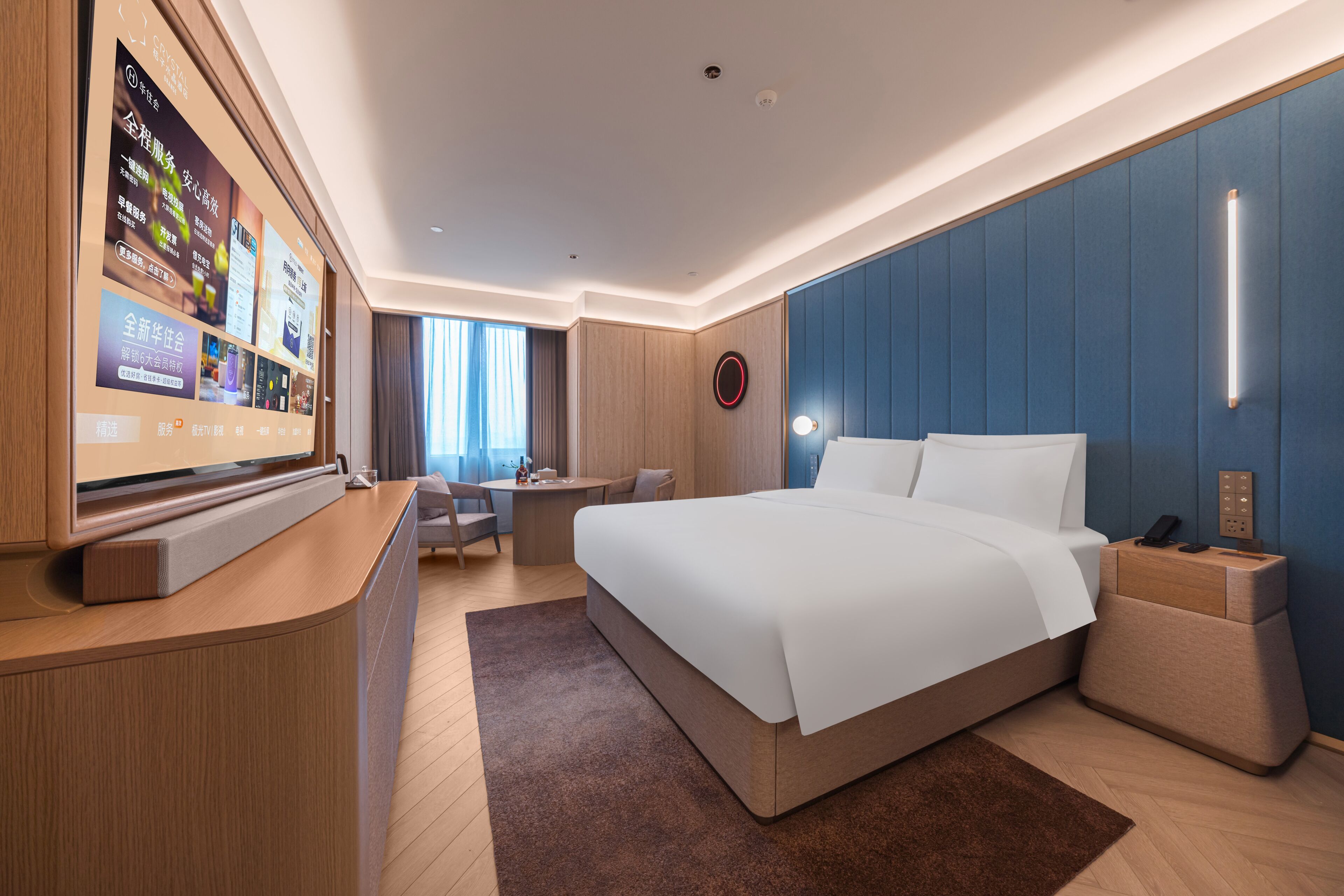 Una habitación de hotel moderna con una cama grande, un escritorio, un televisor y una pared azul decorativa.