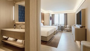 Et moderne hotelværelse med en stor seng, et separat siddeområde, et fjernsyn og et badeværelse med et toiletbord.