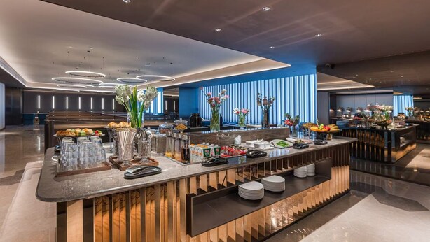 En moderne hotellobby med en receptionsdisk, et buffetområde og en blåstribet væg.
