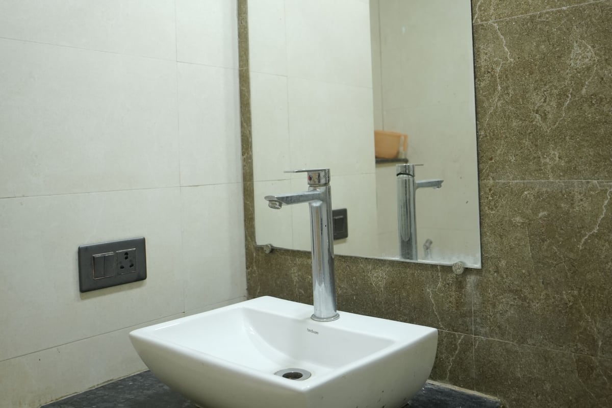 A bathroom with a white sink, a mirror, and a marble countertop.