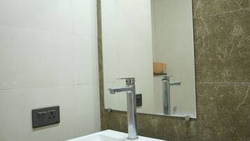 A bathroom with a white sink, a mirror, and a marble countertop.