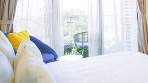 A hotel room with a bed, a small table, and a view of a balcony. - Flamingo Hai Tien Beach Resort (Hoang Tien)