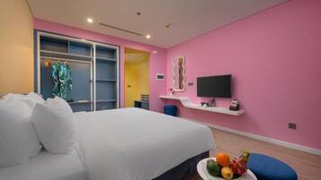 A bedroom with a bed, a small table with fruit, a TV, and a wardrobe.
