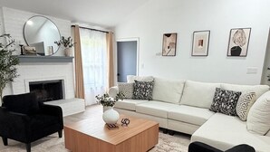 Un salon moderne avec une cheminée, un ventilateur de plafond et un ensemble de canapés.