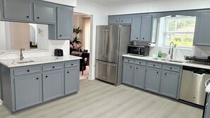 Une cuisine moderne avec des meubles gris, des appareils en acier inoxydable et une grande fenêtre.