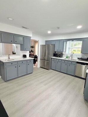 A modern kitchen with grey cabinets, stainless steel appliances, and a large window. - Spring Home near IAH-Houston-Woodlands (Spring)