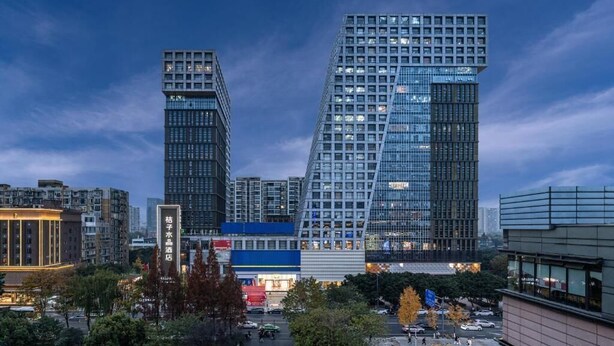 A cityscape with modern high-rise buildings, a prominent blue building with a unique design, and a sign for a water supermarket. - Orange Crystal Hotel Chengdu South Railway Station (Chengdu)