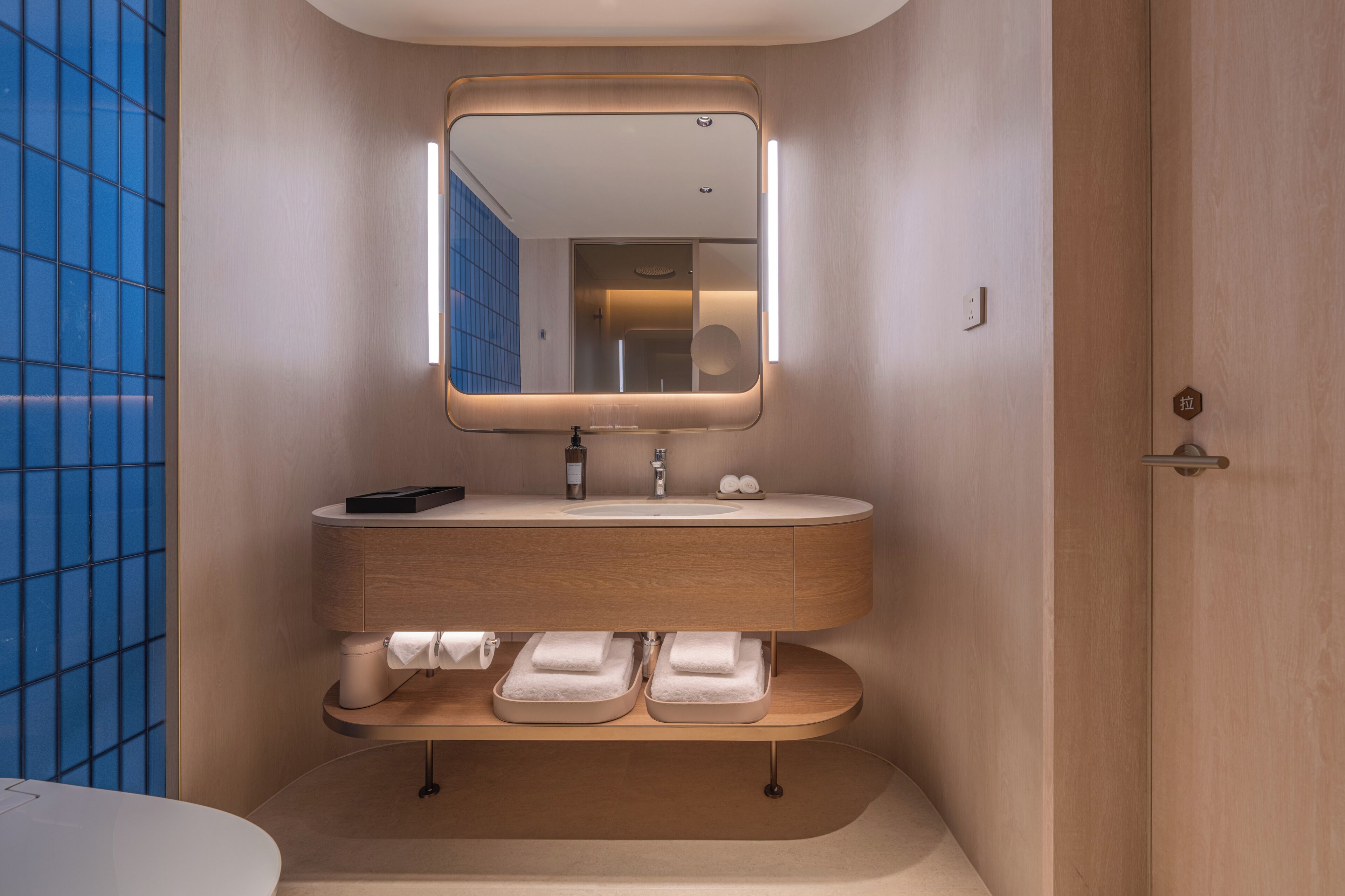 Un baño moderno con un lavamanos redondo, un espejo encima y un perchero debajo.