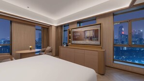 A modern hotel room with a large bed, a desk with a chair, a television, and a city view. - Orange Crystal Hotel Chengdu South Railway Station (Chengdu)
