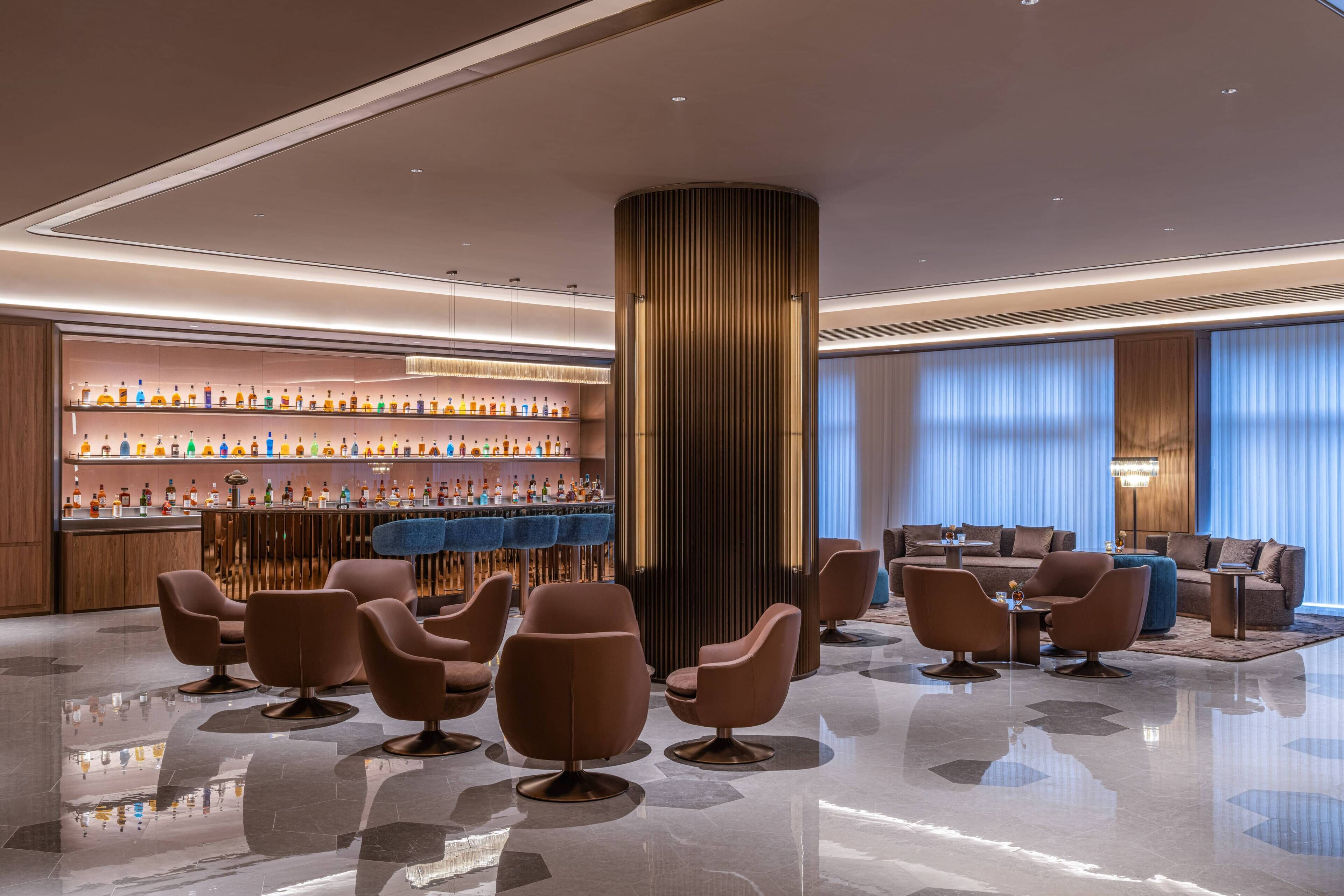 A modern lobby with a bar area, seating, and a large column.
