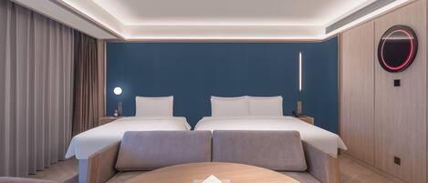 A hotel room with two beds, a round table, and a wall-mounted circular light.