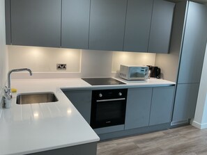 Eine moderne Küche mit grauen Schränken, einem Backofen von Bosch, einer Mikrowelle und einer Kaffeemaschine.