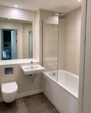 Ein modernes Badezimmer mit einer einteiligen Duschkabine, einer separaten Toilette und einer Badewanne.