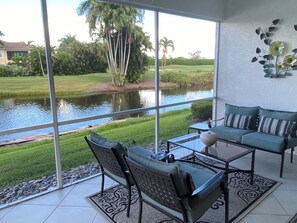 Ein Zimmer mit großem Fenster und Blick auf einen Teich, inklusive Sofa und Sesseln.
