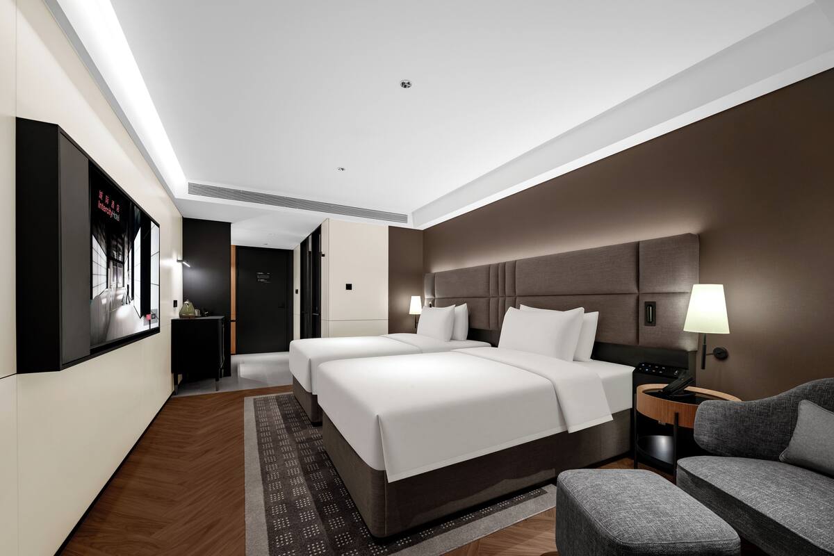 Una habitación de hotel moderna con una cama grande, un escritorio, una silla y un televisor en la pared.