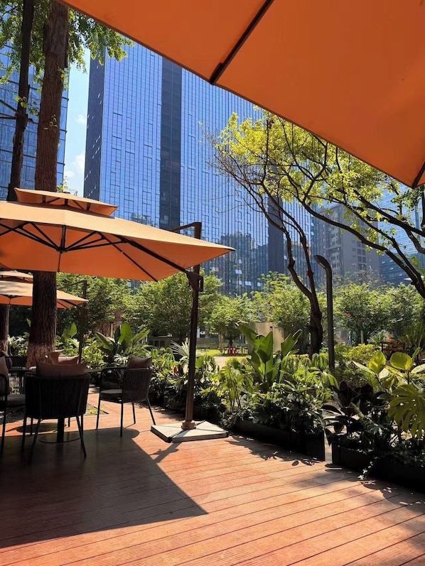 An outdoor patio with wooden flooring, tables, chairs, and orange umbrellas. - IntercityHotel Chengdu Financial City Twin Towers (Chengdu)