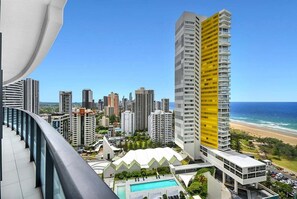 Ein Hochhaus-Hotel mit Pool, umgeben von anderen Gebäuden und einem Strand.