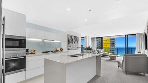 A modern kitchen with built-in appliances, a central island, and a view of the ocean. - Ocean Breeze at Oracle Level 21 (Gold Coast)