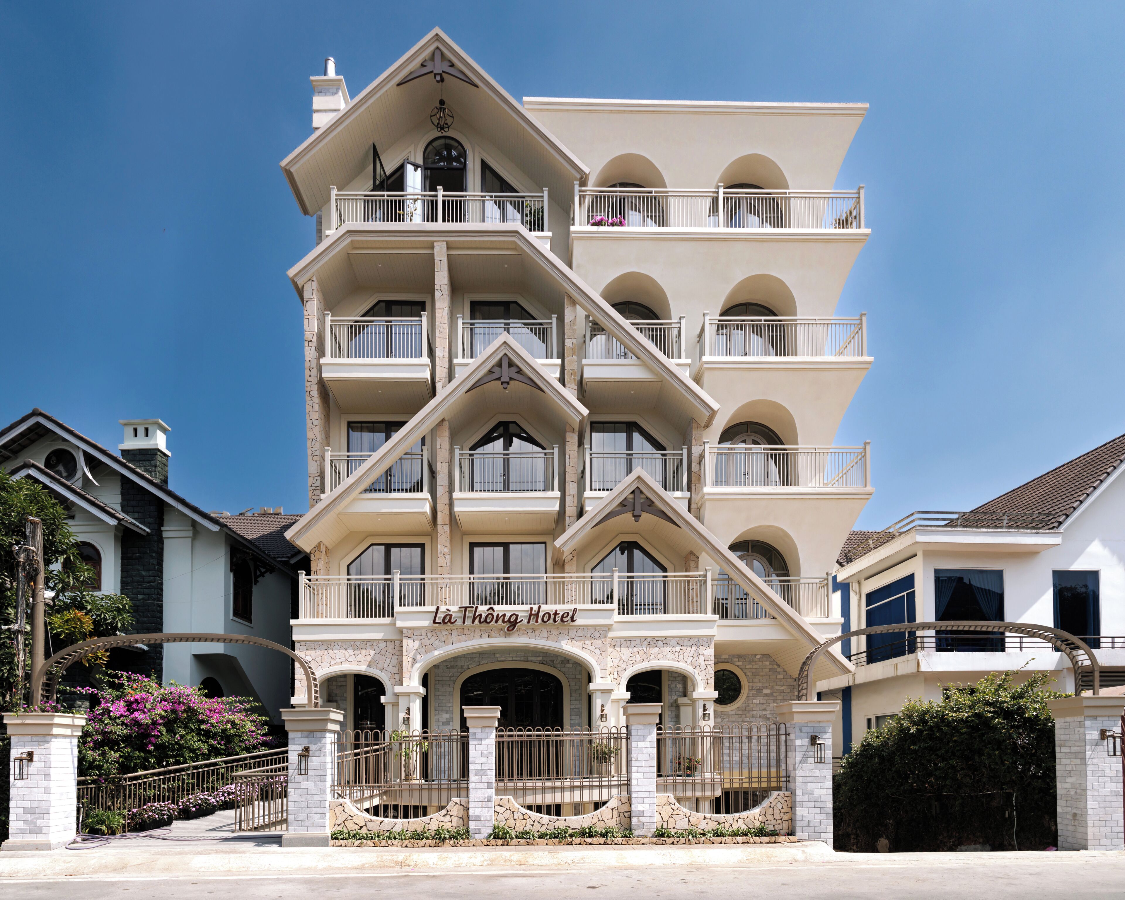 A multi-story hotel with a prominent entrance, balconies, and a clear sky.