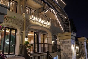 Um hotel com fachada de pedra, varanda e escadaria.