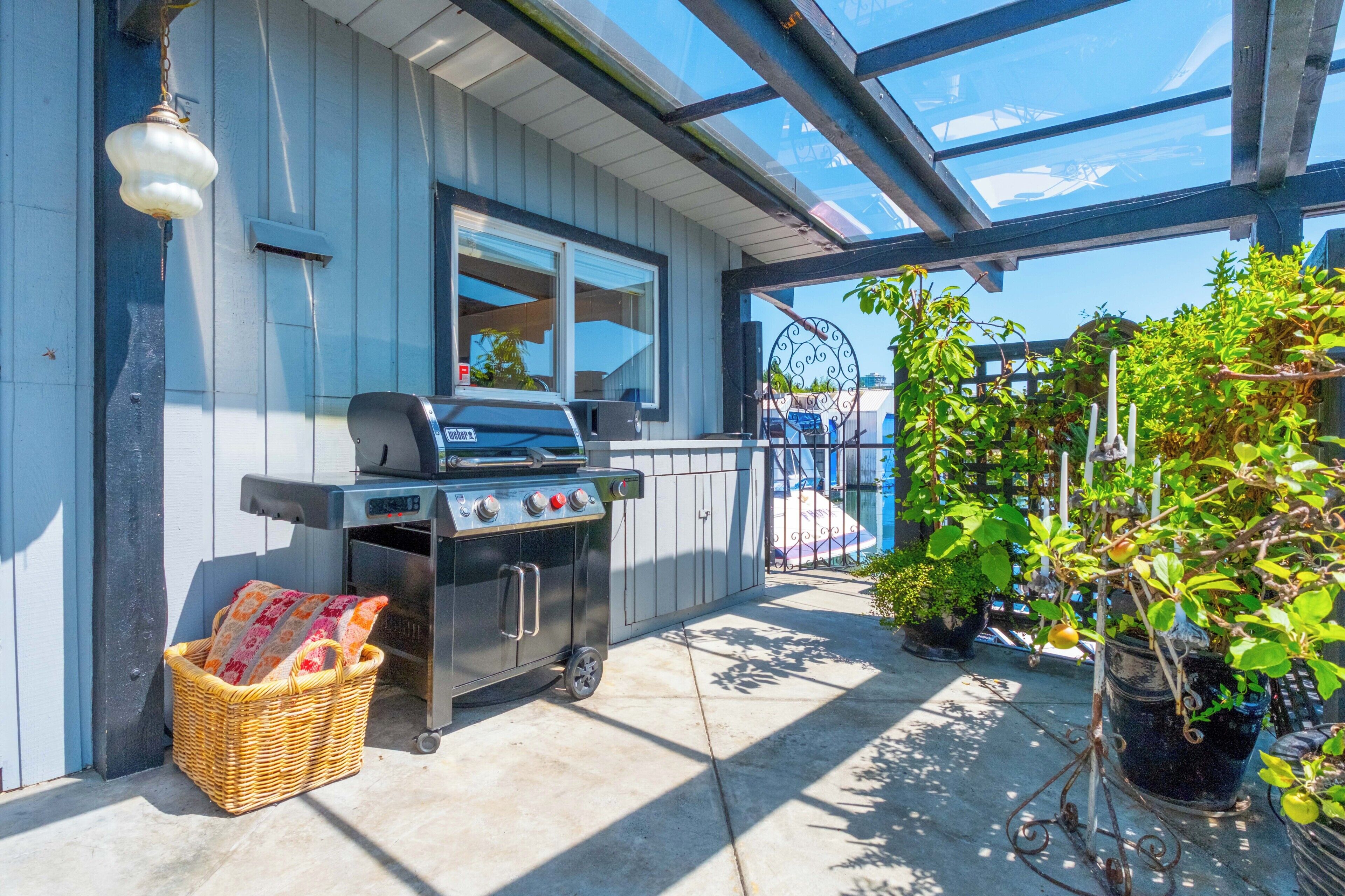 A covered patio with a grill, a wicker basket, and potted plants.