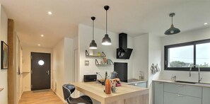 A modern kitchen with a wooden island, pendant lights, and a large window. - Ker Alran - PLENEUF VAL ANDRE (PLENEUF VAL ANDRE)