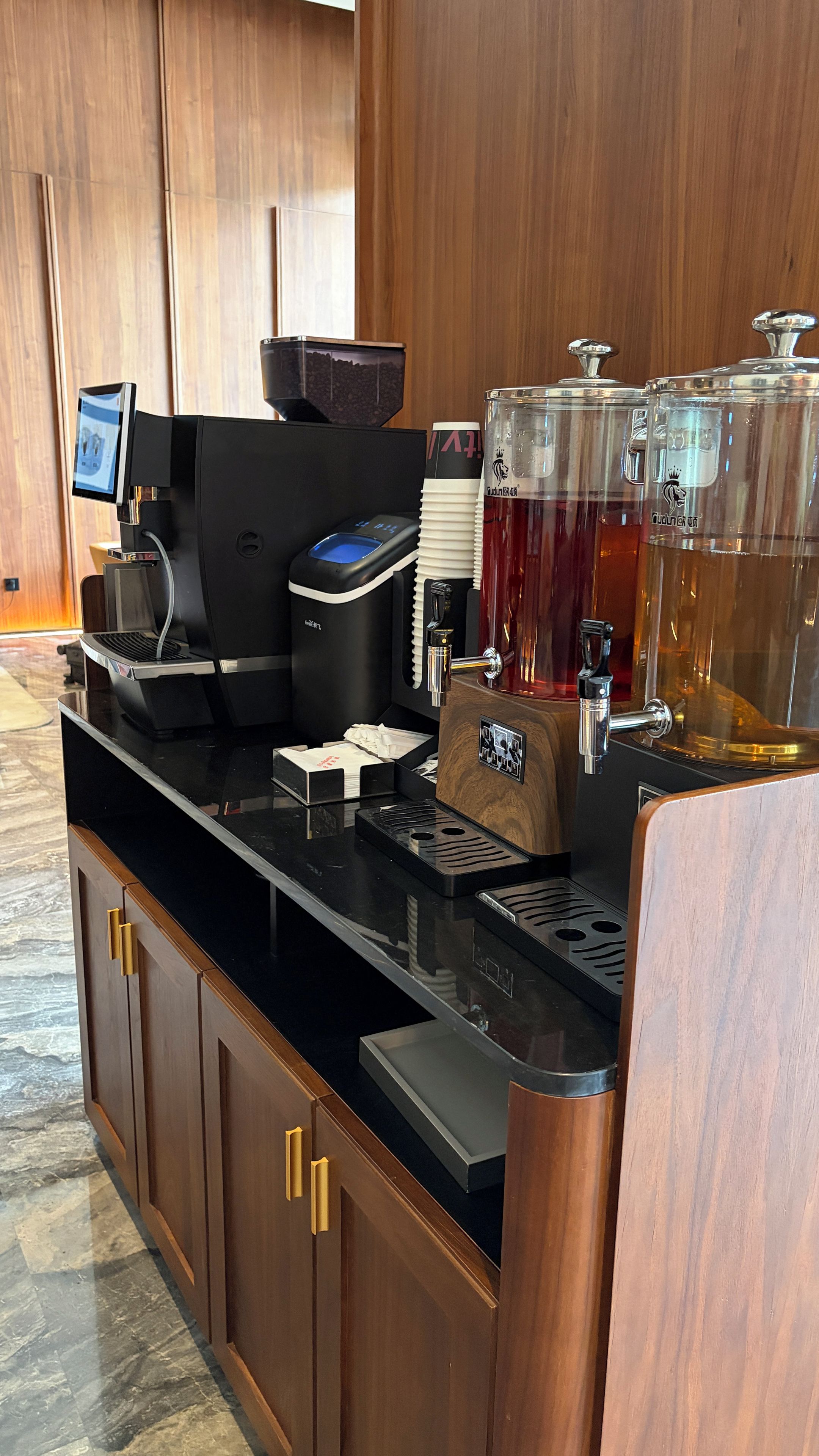 Eine moderne Kaffee-Station mit einem digitalen Bestellbildschirm, einer Kaffeemaschine und einem Getränkeautomaten.