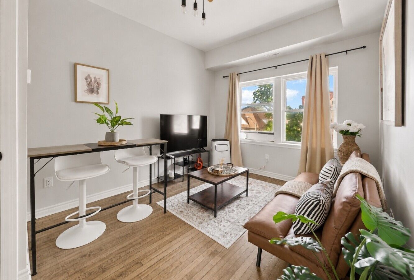 En moderne stue med sofa, fjernsyn og barstole.