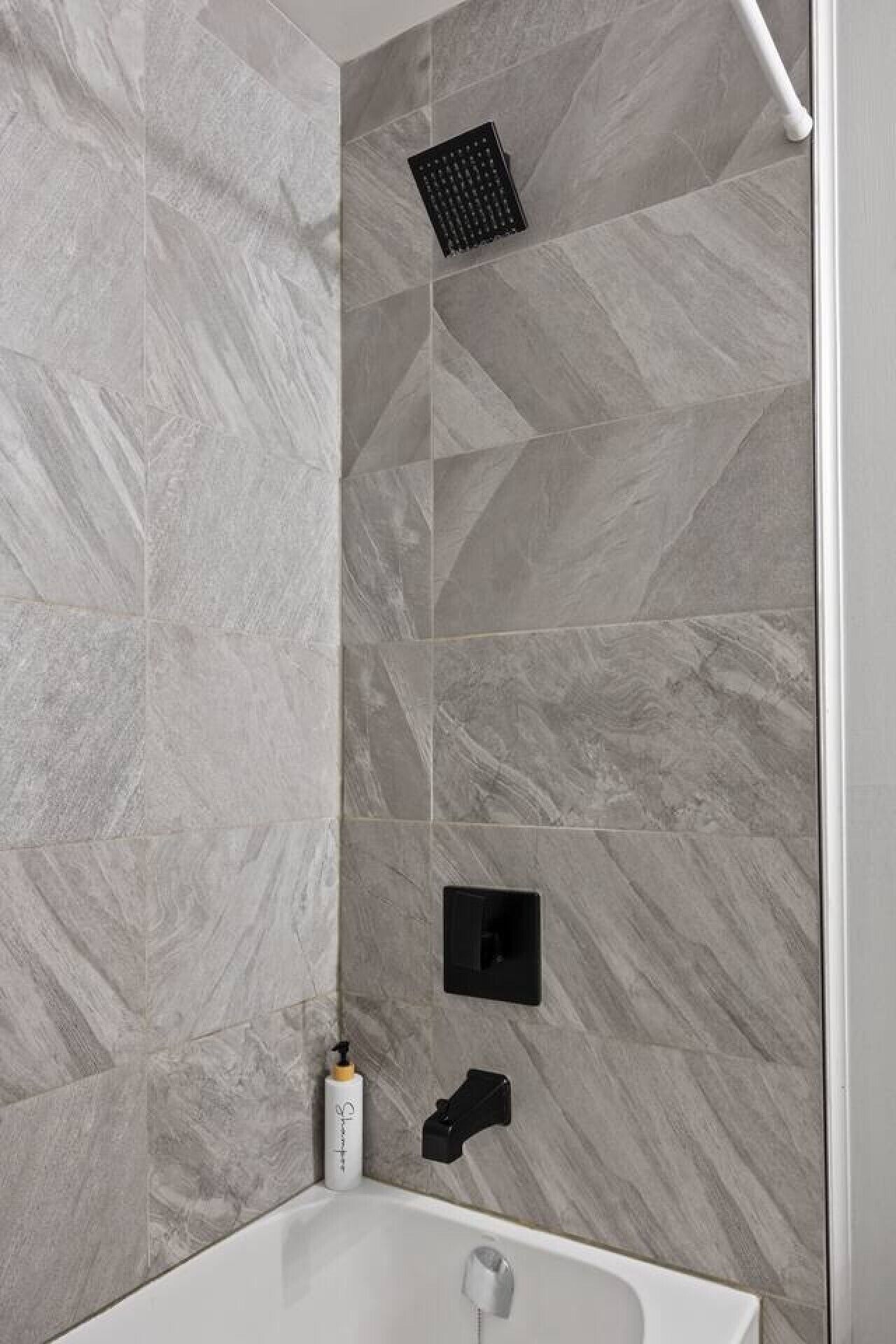 A bathroom with a shower, a white bathtub, and a wall-mounted faucet.