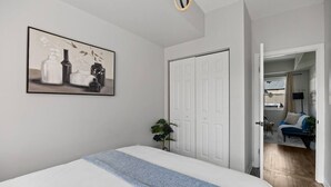 Een slaapkamer met een bed, een deur, een gang en een zithoek met een bank.
