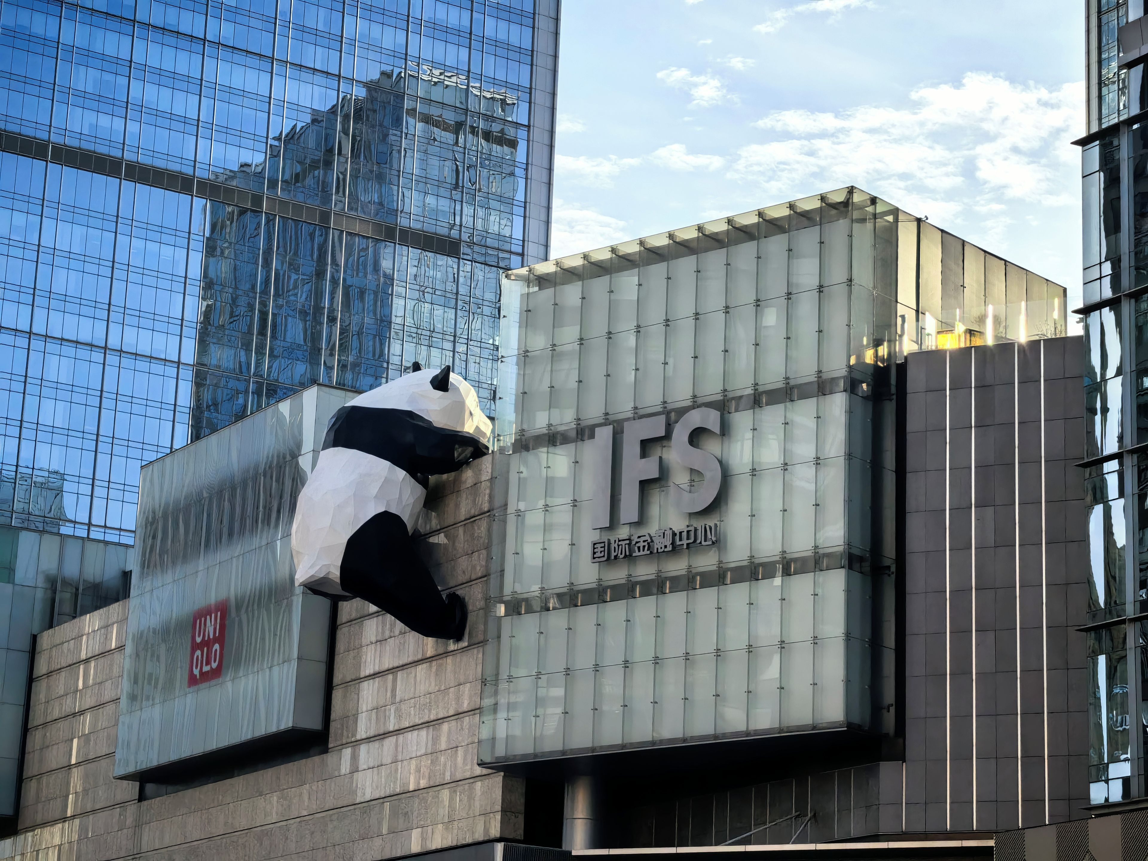 Un bâtiment doté d’une façade en verre et d’une grande sculpture de panda sur le côté.
