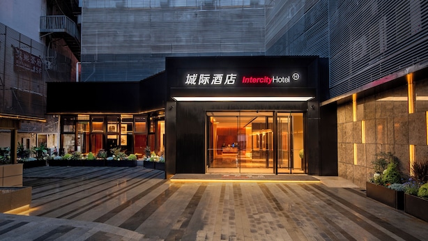 A modern hotel entrance with a glass facade, a sign in both Chinese and English, and a well-lit outdoor area with plants. - IntercityHotel Taikoo Li Chunxi Rd (Chengdu)