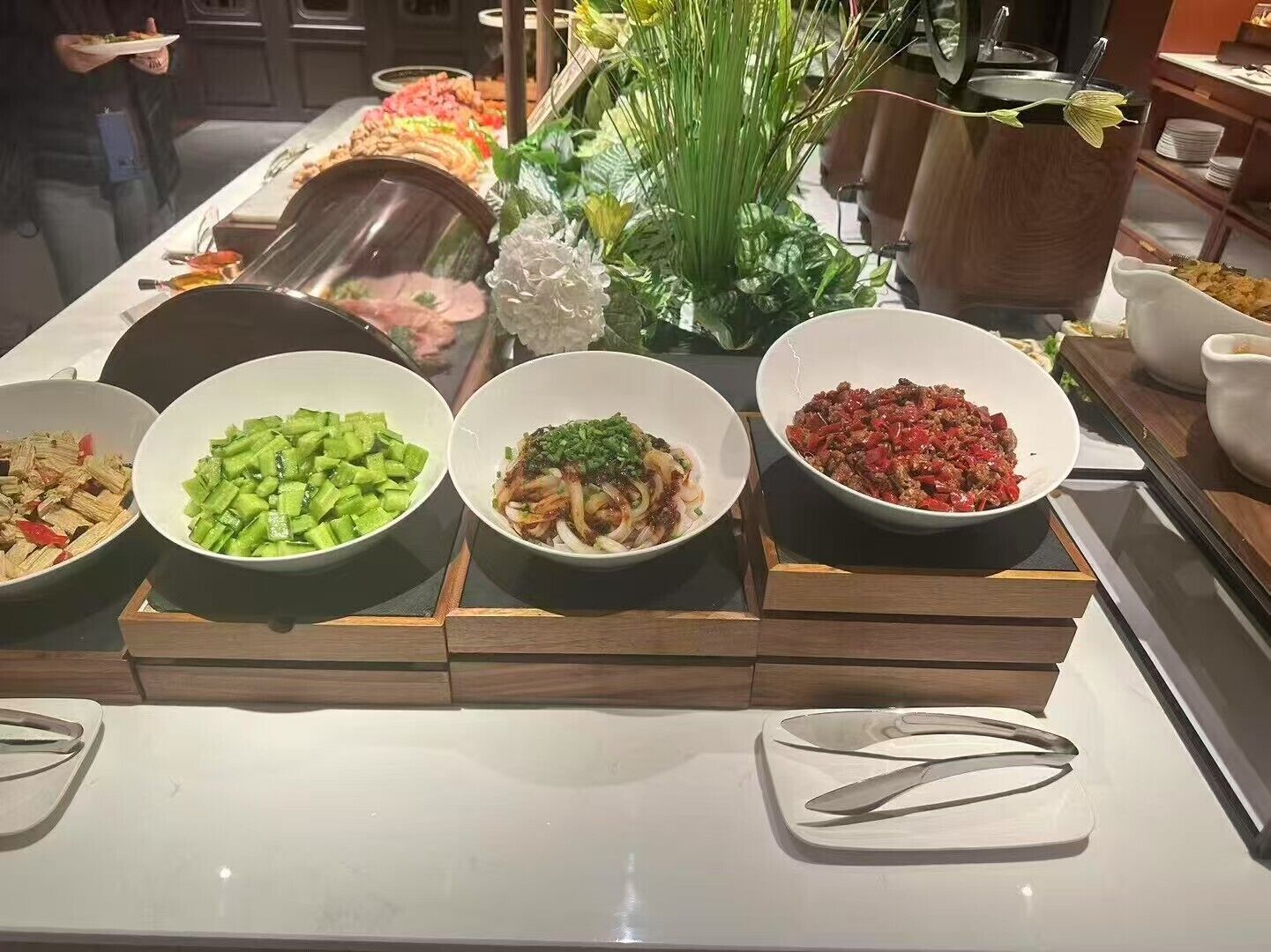 A buffet with various dishes including vegetables, meat, and a decorative centerpiece.