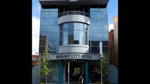 Un bâtiment moderne doté d’une façade en verre incurvée, d’une entrée imposante et d’une enseigne indiquant « HOBART CITY HOTEL ».