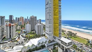 A high-rise hotel with a distinctive yellow facade, located near a beach with a view of the ocean. - Ocean Perfection at Oracle Level 23 (Gold Coast City)