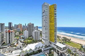 A high-rise hotel with a distinctive yellow facade, located near a beach with a view of the ocean. - Ocean Perfection at Oracle Level 23 (Gold Coast City)