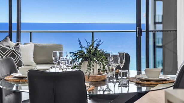 A dining area with a view of the ocean, a potted plant, and a modern table setting. - Ocean Perfection at Oracle Level 23 (Gold Coast City)