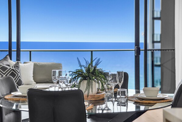 A dining area with a view of the ocean, a potted plant, and a modern table setting. - Ocean Perfection at Oracle Level 23 (Gold Coast City)