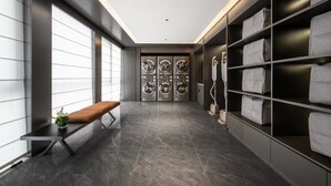 Um corredor moderno com um banco, um telefone e uma área de lavandaria com várias máquinas de lavar.